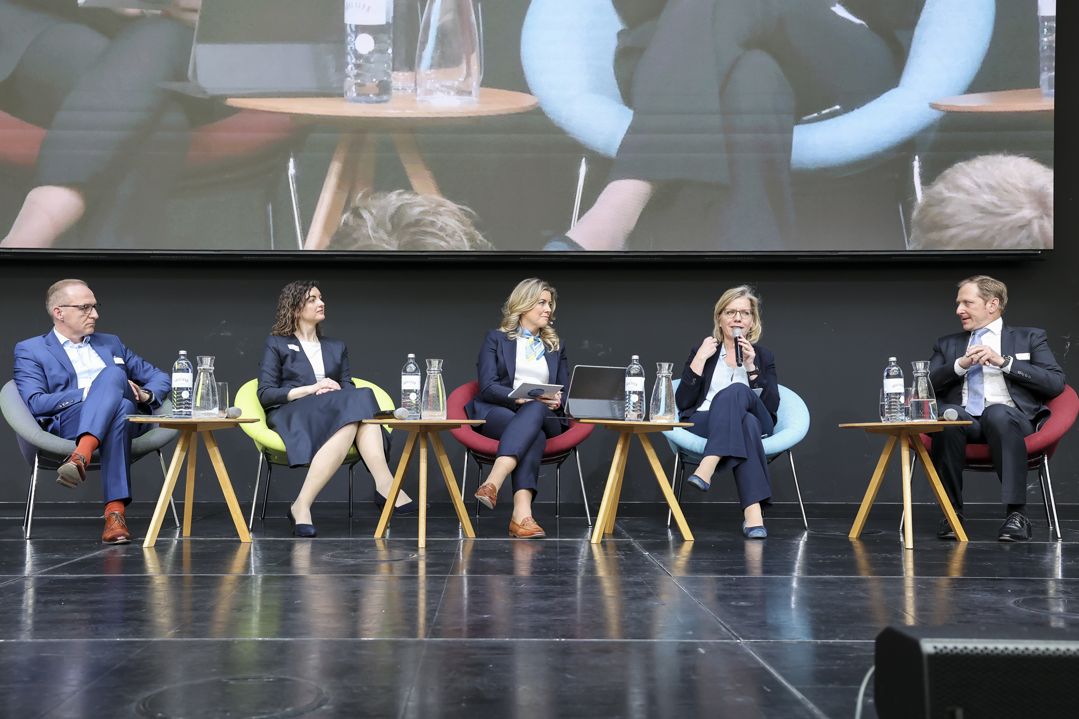 5 Personen die bei einer Podiumsdiskussion auf der Bühne sitzen